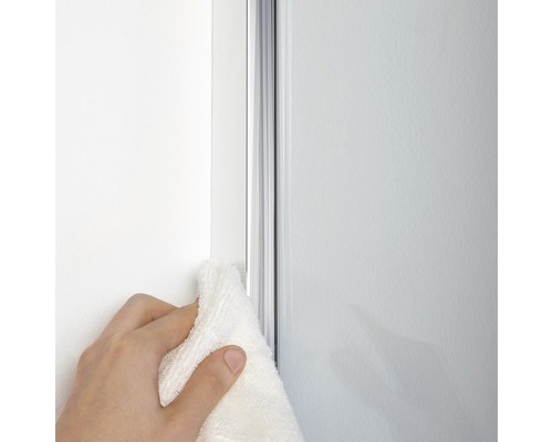 Une main essuie un joint de douche avec un chiffon.