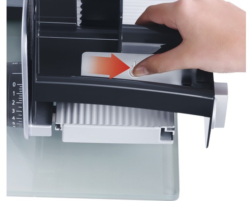 Bedienung einer Aufschnittmaschine: Eine Hand drückt einen Schieber mit Pfeilsymbol.