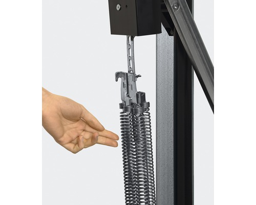 Detailaufnahme einer Hand, die auf Zugfedern an einer Garagentorkonstruktion zeigt.