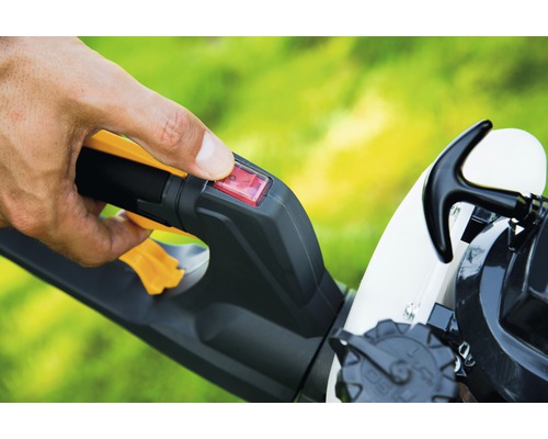 Gros plan d''une commande sur un outil de jardin avec un doigt sur un interrupteur rouge