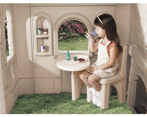 Fille buvant à table dans une cabane de jeu