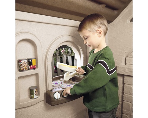 Garçon jouant avec une cuisine jouet dans une cabane pour enfants