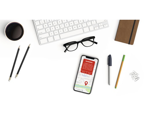 Clavier, lunettes, smartphone avec message d''avertissement, carnet et stylos sur un bureau