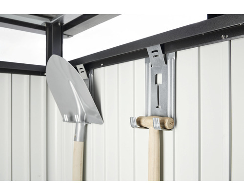 Eine Schaufel und ein Hammer hängen an einer Wandhalterung in einem Gartenschrank.