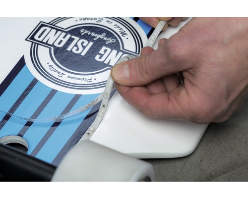 Eine Person befestigt LED-Streifen an einem Longboard.