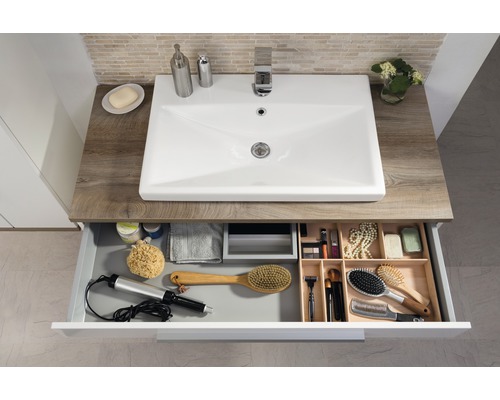 Badezimmerwaschtisch mit offenem Schubfach und diversen Badutensilien