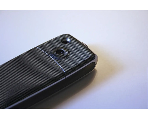 Detailansicht eines elektronischen Geräts mit Kohlefasermuster und zwei Aussparungen.