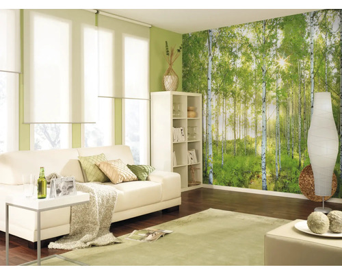 Salon lumineux avec canapé, étagère, lampadaire, tapis et papier peint forêt