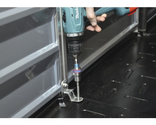 Visseuse sans fil Makita fixant un rail métallique au sol.