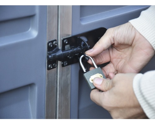 Une personne fixe un cadenas à un verrou sur une porte