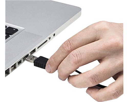 Eine Hand steckt einen USB-Stecker in einen Laptop