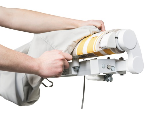 Person zieht eine Schutzhülle über eine Markise mit Streifenmuster.