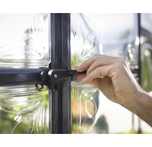 Nahaufnahme einer Hand, die einen Fenstergriff an einem Gewächshaus bedient