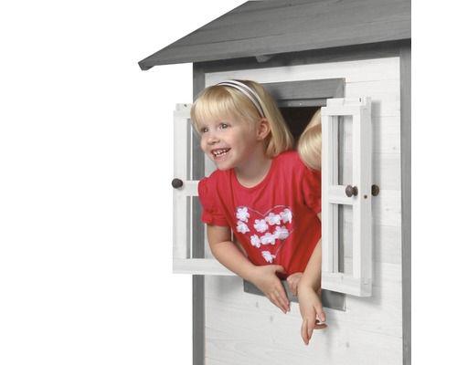 Fille regardant par la fenêtre d''une cabane de jeux en bois