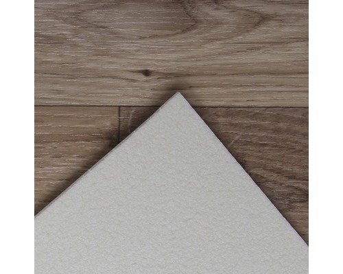 Vue détaillée d''un carreau de vinyle blanc sur un plancher en bois.