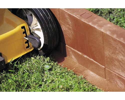 Gros plan d''une tondeuse à gazon près d''une bordure de pelouse.