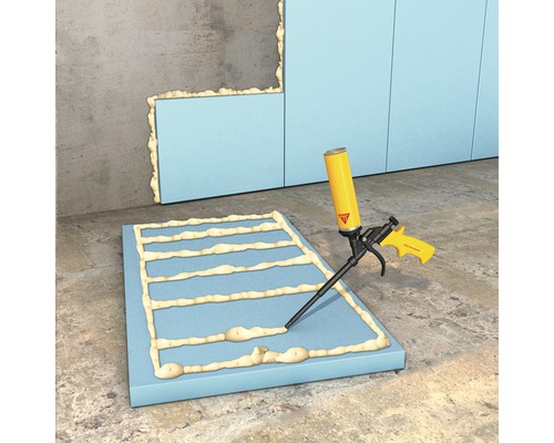 Scène avec plaques isolantes, colle de montage et pistolet à colle pour isolation murale