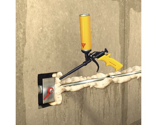 Application de mousse expansive avec un pistolet à mousse pour sceller un passage mural.