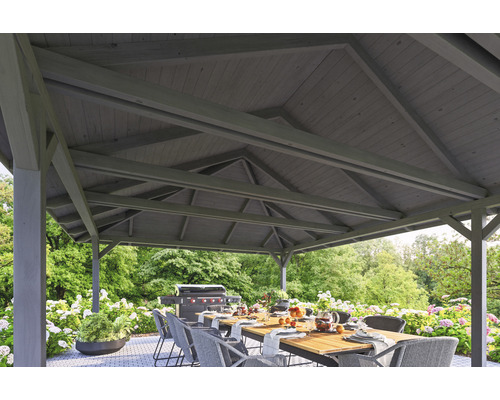 Pavillon avec toit en bois, table à manger et barbecue dans le jardin