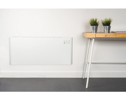 An der Wand montierter, flacher Heizkörper neben einem Schreibtisch mit Pflanzen.