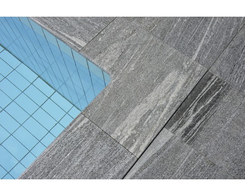 Nahaufnahme von grauen Steinplatten neben einer Glasfassade