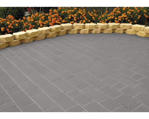 Verlegter grauer Pflasterbelag mit gelbem Rand und Blumenbeet