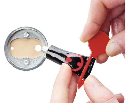 Eine Klebstofftube wird mit einem roten Applikator geöffnet, um Klebstoff aufzutragen