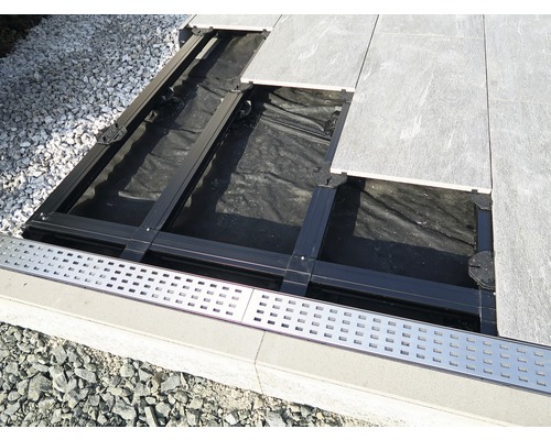 Aufbau einer Terrassenkonstruktion mit Platten, Unterkonstruktion und Entwässerungsrinne.