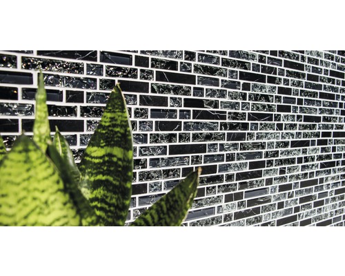 Mur avec des carreaux de mosaïque de forme rectangulaire et une plante au premier plan