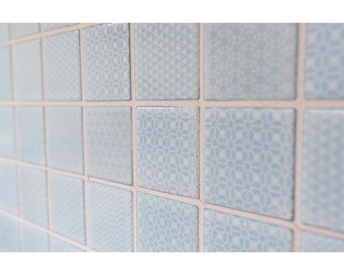 Nahaufnahme von hellblauen, quadratischen Wandfliesen mit verschiedenen Mustern