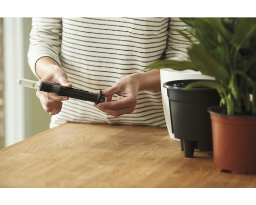 Une personne assemble un capteur d''humidité pour pots de fleurs.