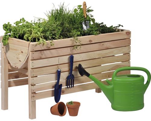 Hochbeet aus Holz mit Kräutern, Gartengeräten und Giesskanne
