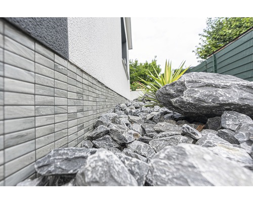 Mur de maison avec revêtement de soubassement et pierres dans le jardin