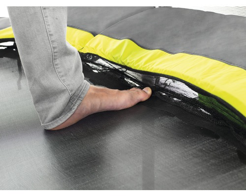 Vue détaillée d''une personne pieds nus sur un trampoline avec filet de sécurité.