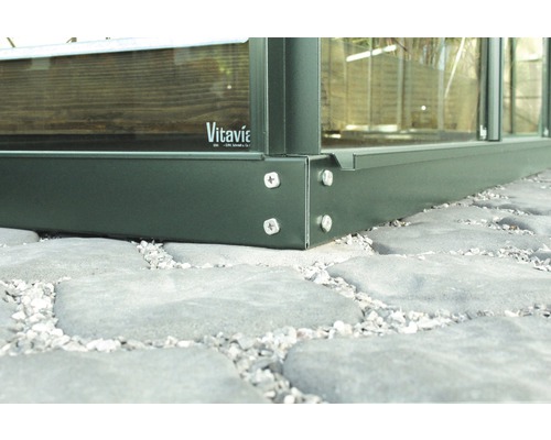 Vue détaillée d''une fondation de serre avec des vis sur des pavés