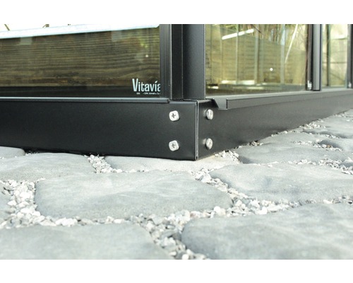 Vue détaillée d''une fondation de serre en métal avec vis sur un sol en pierre