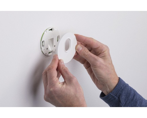 Eine Person montiert eine runde Wandhalterung an einer Wand