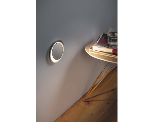 Wandleuchte neben kleinem Tisch mit Glas und Büchern an der Wand