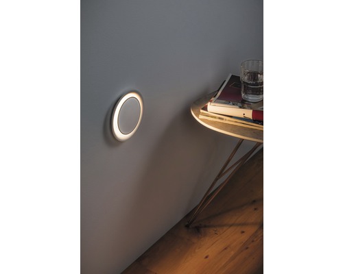 Wandleuchte neben einem Beistelltisch mit Zeitschriften und einem Glas Wasser