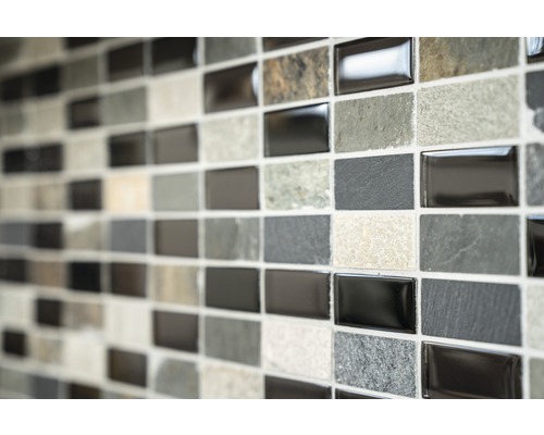 Mosaikfliesenwand mit rechteckigen Fliesen in verschiedenen Grautönen und Texturen
