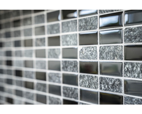 Nahaufnahme einer Mosaikfliesenwand mit abwechselnd glänzenden und steinartigen Oberflächen