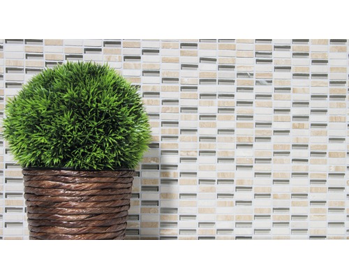 Plante artificielle décorative en pot devant un fond de mosaïque