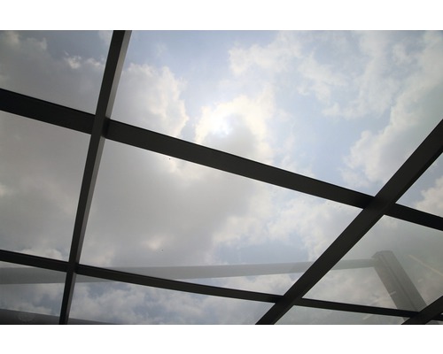 Ansicht einer Glasdachkonstruktion mit Himmel und Wolken im Hintergrund.