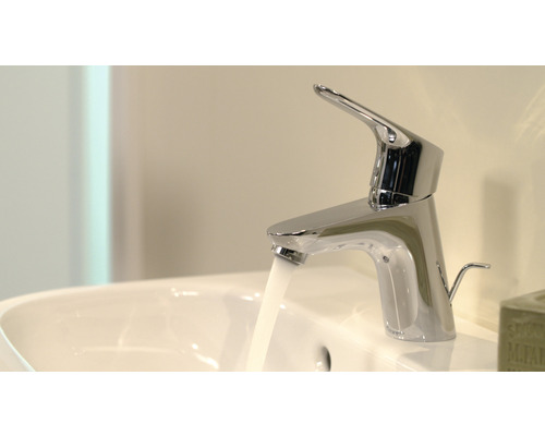 Wasserhahn aus Metall mit fließendem Wasser im Waschbecken