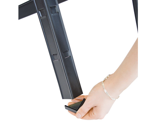 Main fixant une pièce d''angle sur une étagère métallique