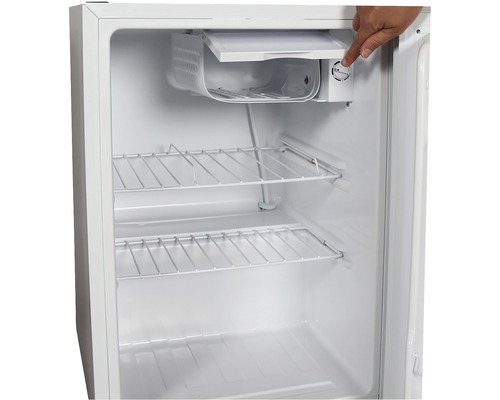 Innenraum eines weißen Kühlschranks mit Drahtregalen und einer Person, die einen Regler bedient