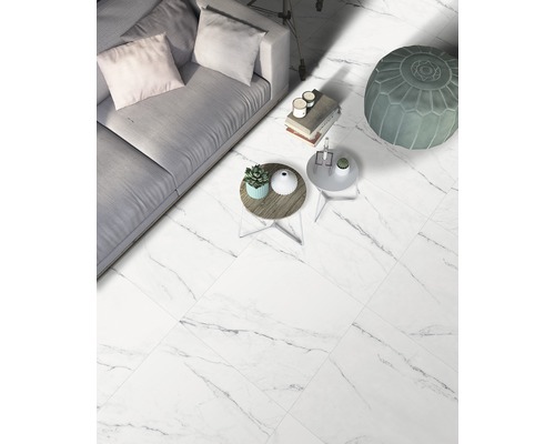 Salon lumineux avec carrelage aspect marbre, canapé et tables d''appoint.