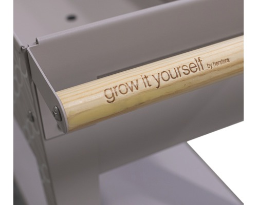 "Detailansicht eines Kräuterwagens mit Holzgriff und der Aufschrift ""grow it yourself by herstera""."
