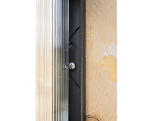 Vue détaillée d''une plaque alvéolaire transparente, fixée avec une vis et un clip de fixation sur un cadre