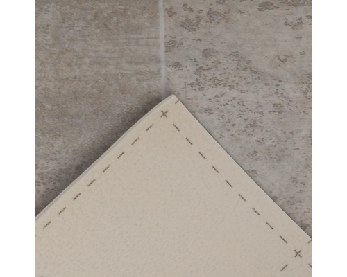 Detailansicht eines Teppichs mit gesteppten Kanten auf einem Fliesenboden.